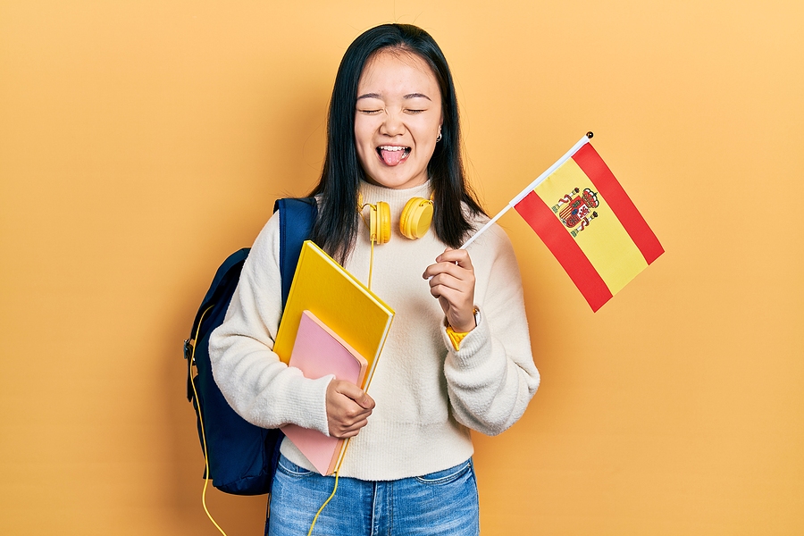 young-chinese-girl-exchange-student-holding-spanish-flag-stickin