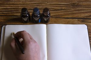 close-up-of-a-fountain-pen-on-a-notebook-and-several-inkwells-c