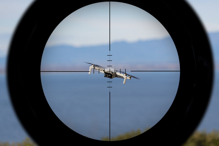 gun-sight-pointing-at-a-drone-flying-with-the-ocean-in-the-backg