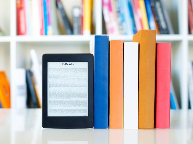 ebook-reader-and-paper-books-on-bookshelf-background