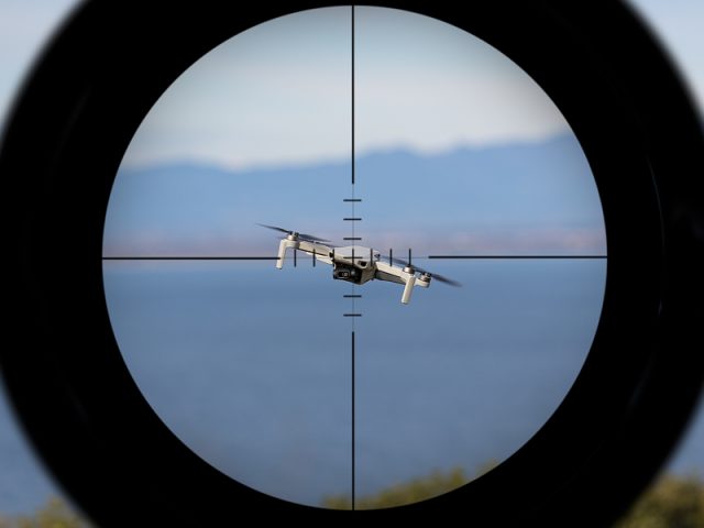 gun-sight-pointing-at-a-drone-flying-with-the-ocean-in-the-backg