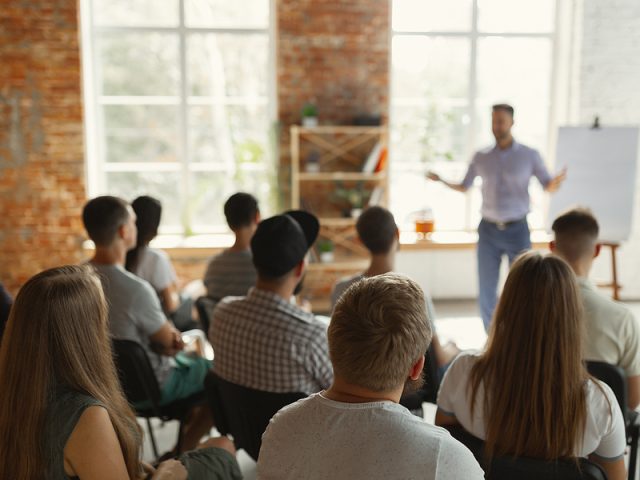 male-speaker-giving-presentation-in-hall-at-university-workshop