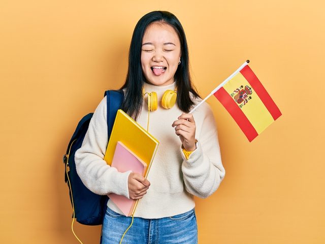 young-chinese-girl-exchange-student-holding-spanish-flag-stickin