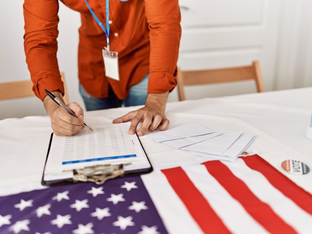 young-hispanic-man-writing-on-checklist-at-electoral-college