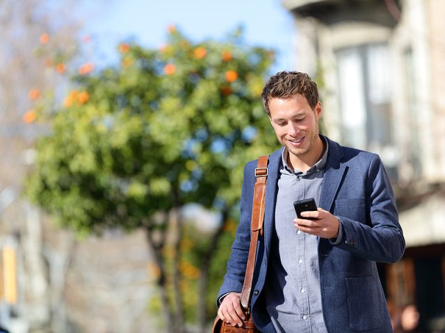 young-urban-professional-man-using-smart-phone-businessman-hold